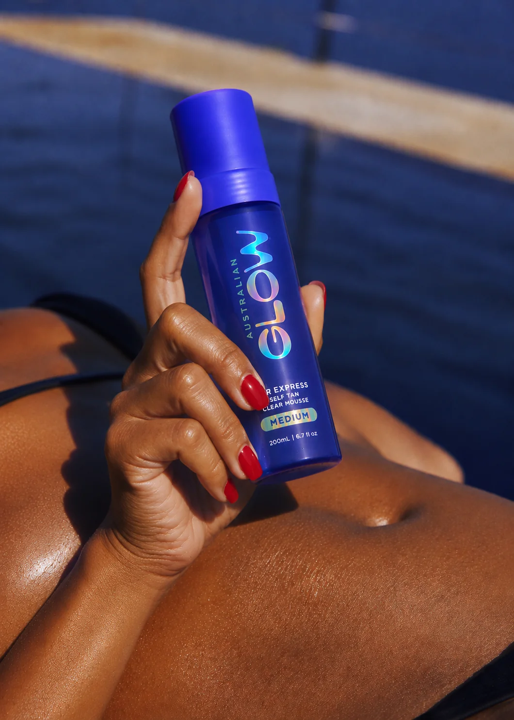 Australian Glow poolside, bronzed hand holding 1HR Express bottle