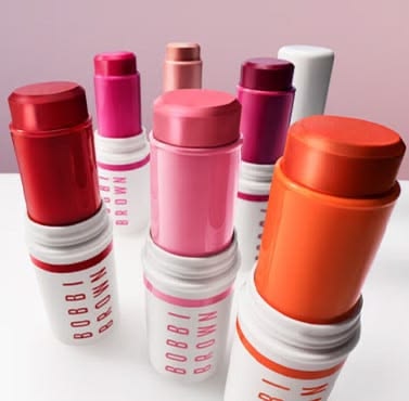 Bobbi Brown Crushed Lip Color sticks in plum, red and rose on pink