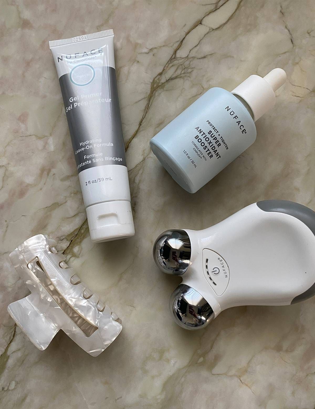 NuFACE Mini, Gel Primer and Antioxidant Booster flatlay on marble, the device system